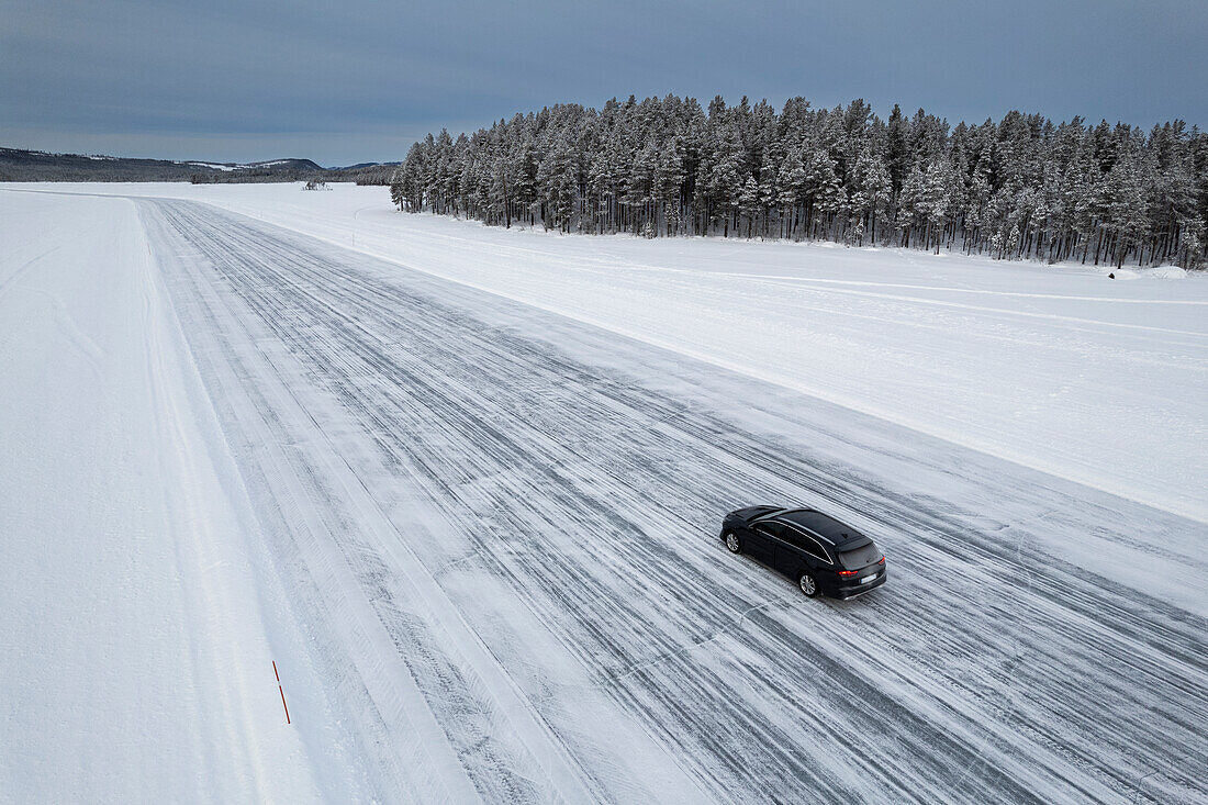 Auto auf einer Eispiste auf einem zugefrorenen See in der schneebedeckten Landschaft, Jokkmokk, Norrbotten, Lappland, Schweden, Scaninavien, Europa