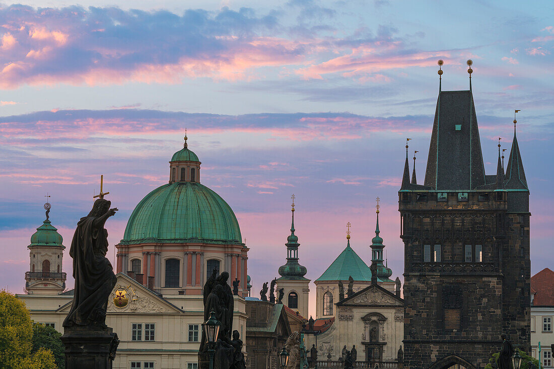 Details von Statuen und Türmen an der Karlsbrücke bei Sonnenaufgang, mit der Kuppel der Kirche des Heiligen Franz von Assisi und dem Altstädter Brückenturm, UNESCO-Weltkulturerbe Prag, Böhmen, Tschechische Republik (Tschechien), Europa