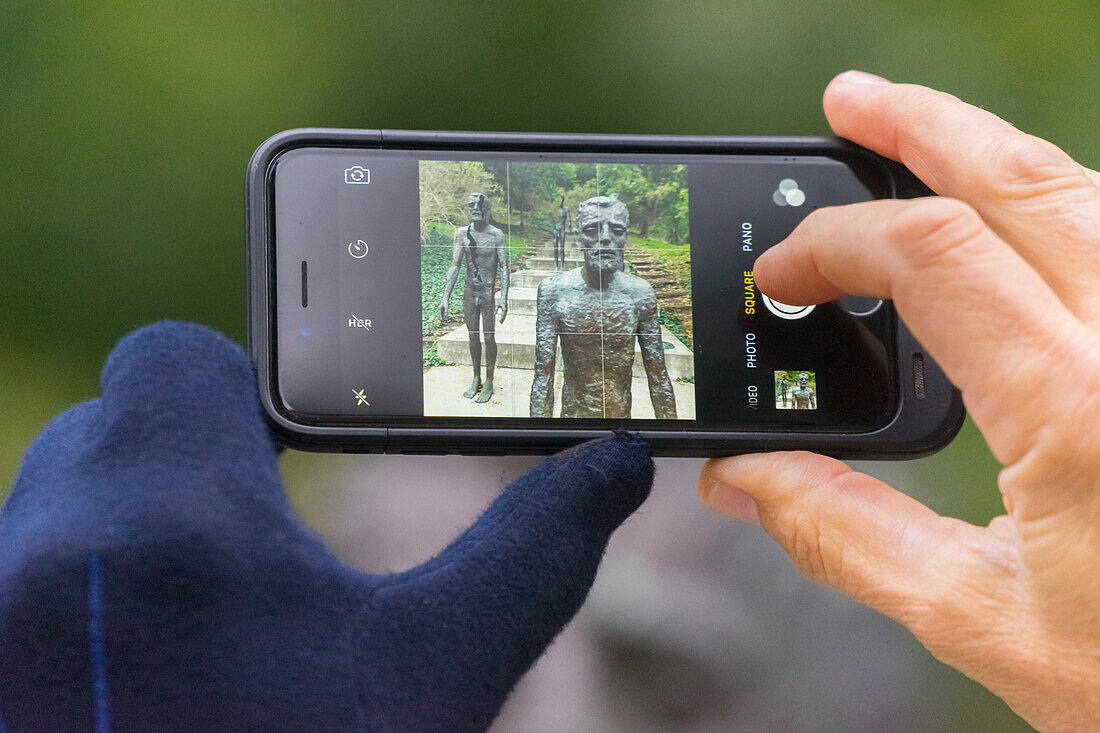 Detail der Hände mit Handy, die auf die Statuen am Denkmal für die Opfer des Kommunismus schießen, Prag, Böhmen, Tschechische Republik (Tschechien), Europa