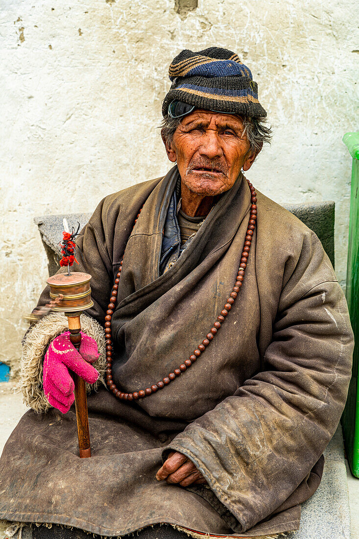 Old man with a prayer wheel in his hand, Kingdom of Mustang, Nepal, Asia