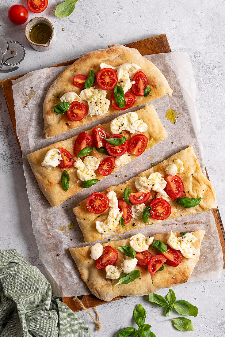 Pinsa with tomatoes, mozzarella, basil, and olive oil
