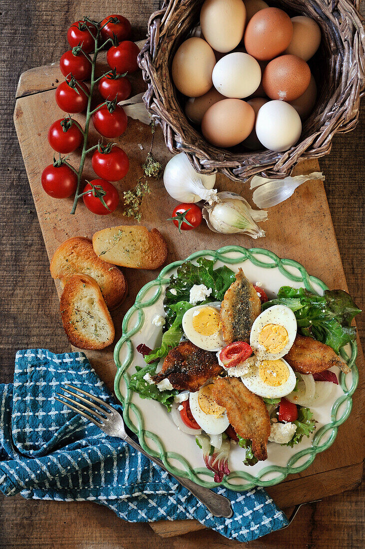Salad with fried fish, boiled eggs and feta cheese