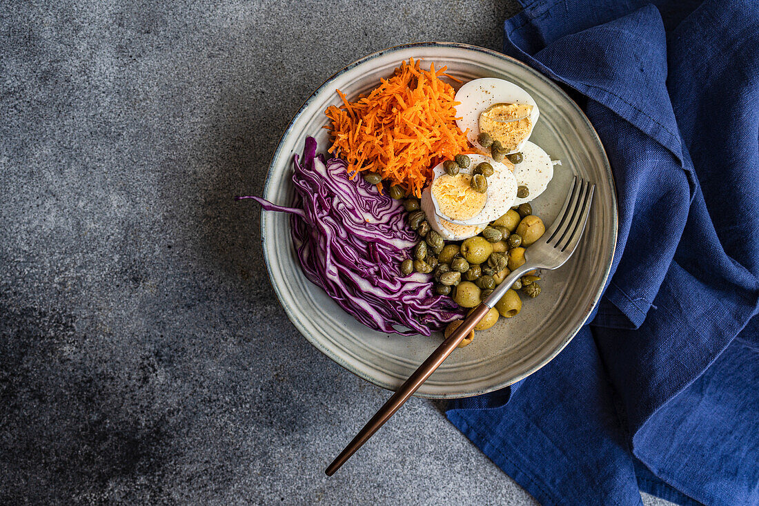 Bowl mit gekochten Eiern, Kapern, Oliven, Rotkohl und Möhren (Keto-Küche)