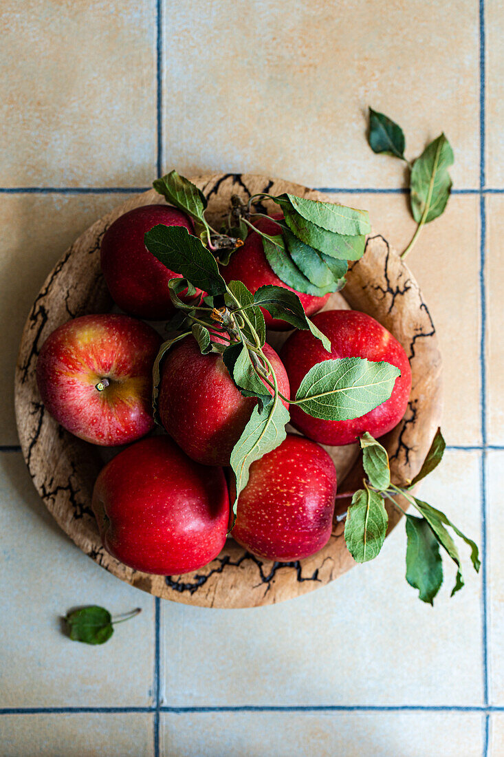 Wooden bowl with red apples on tiled kitchen table