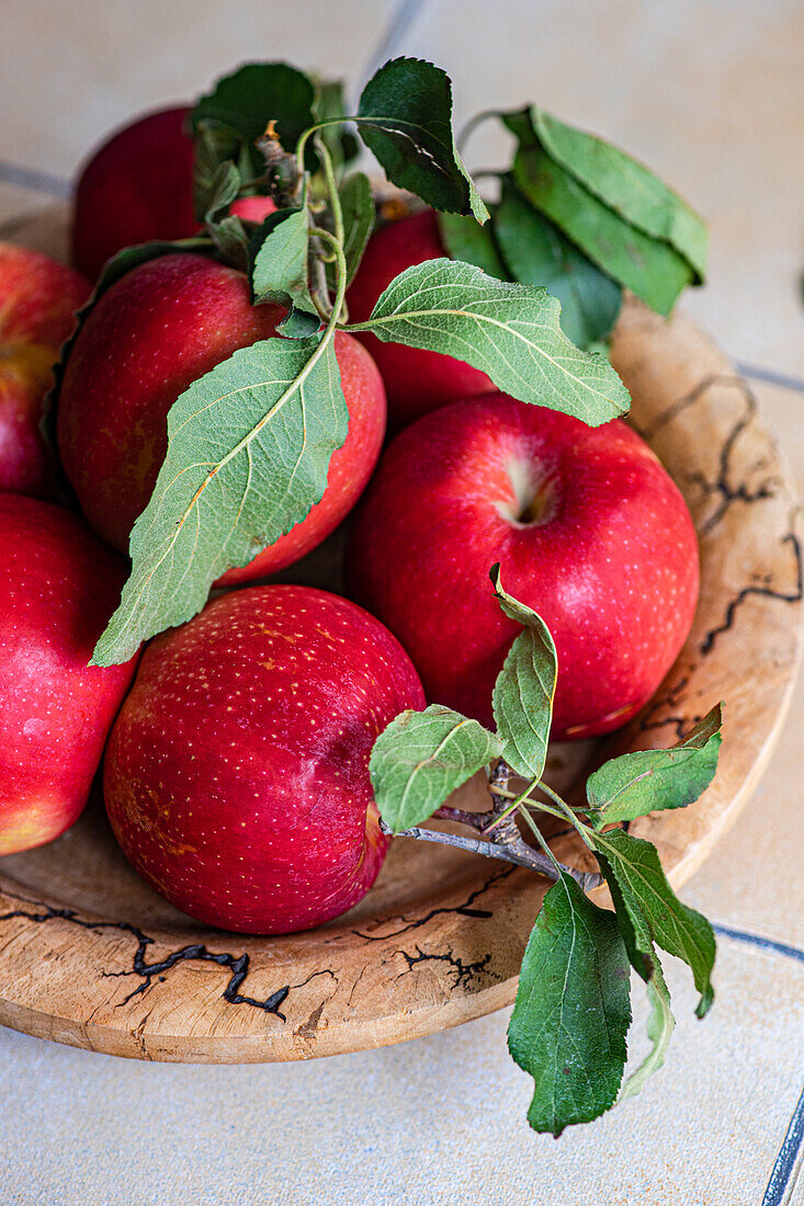 Wooden bowl with red apples on tiled kitchen table