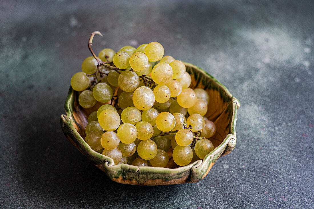 Green organic grapes in a bowl on a dark table