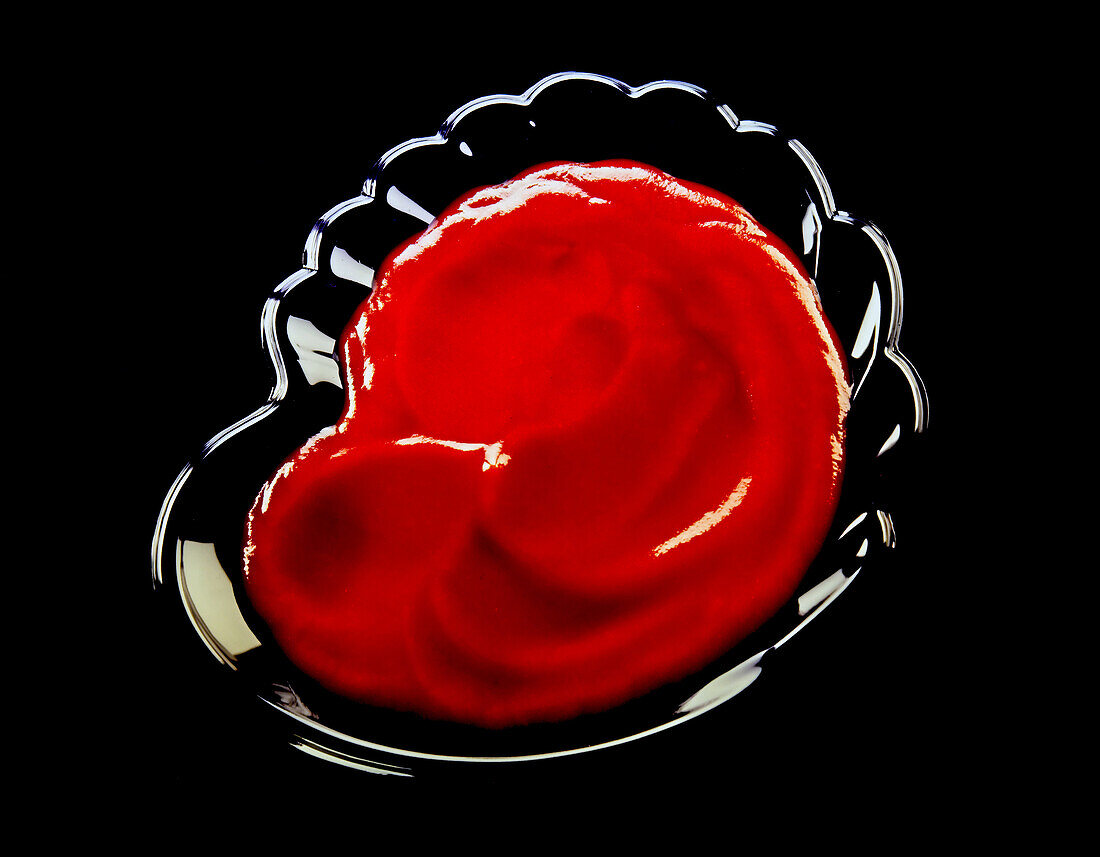 Schälchen mit Ketchup auf schwarzem Untergrund