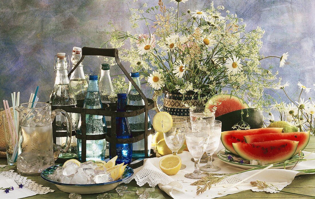 Still life with water, ice cubes & watermelons on table