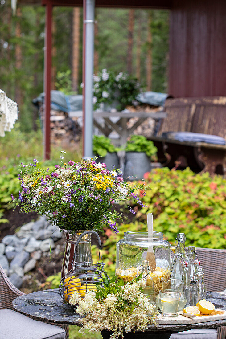 Terrassentisch mit frischen Sommerblumen und Getränken im Freien