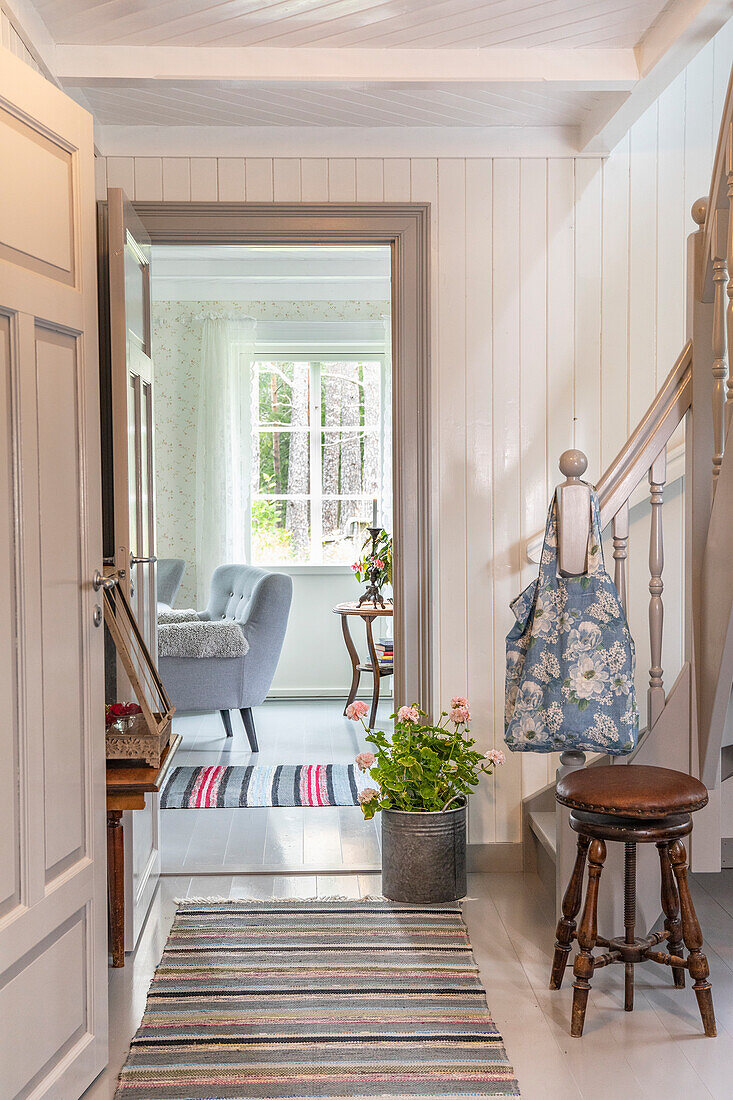 Hallway with wooden staircase, plant in a zinc bucket and striped runner