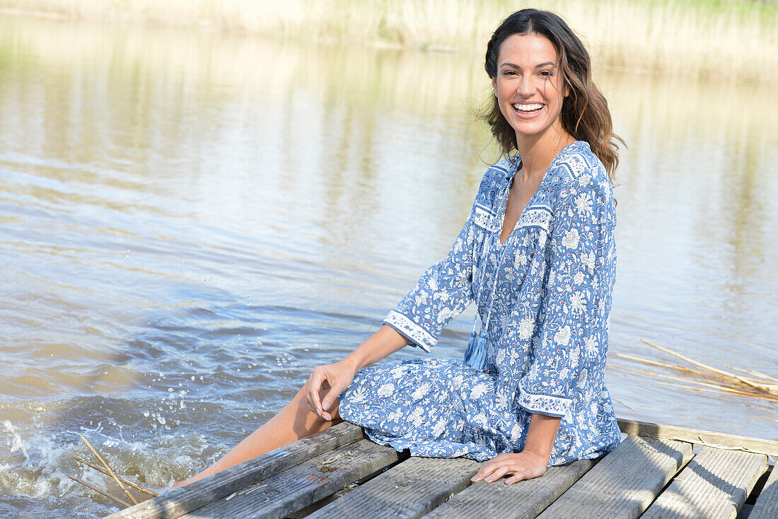Brunette woman sitting on a wooden pier by the lake