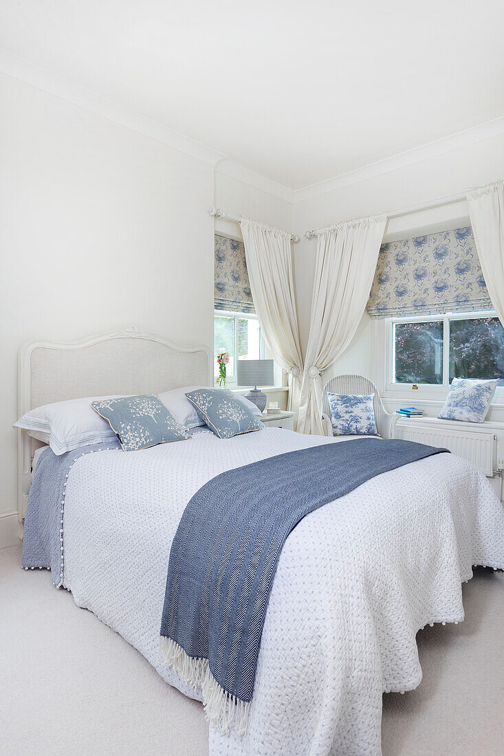 Bedroom with white and blue bed linen and patterned fabric blinds