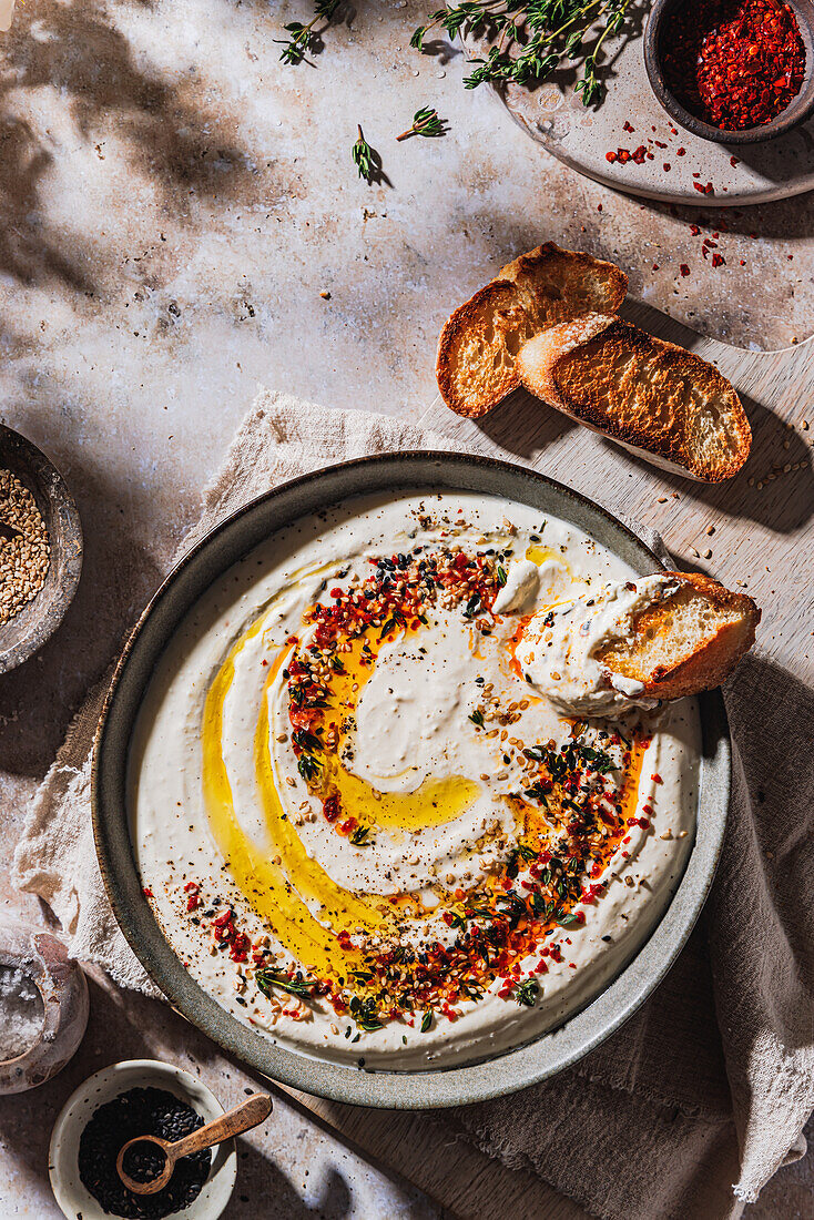 Dip aus Feta-Käse und Joghurt mit Topping aus Olivenöl, Chili, Sesam und Thymian