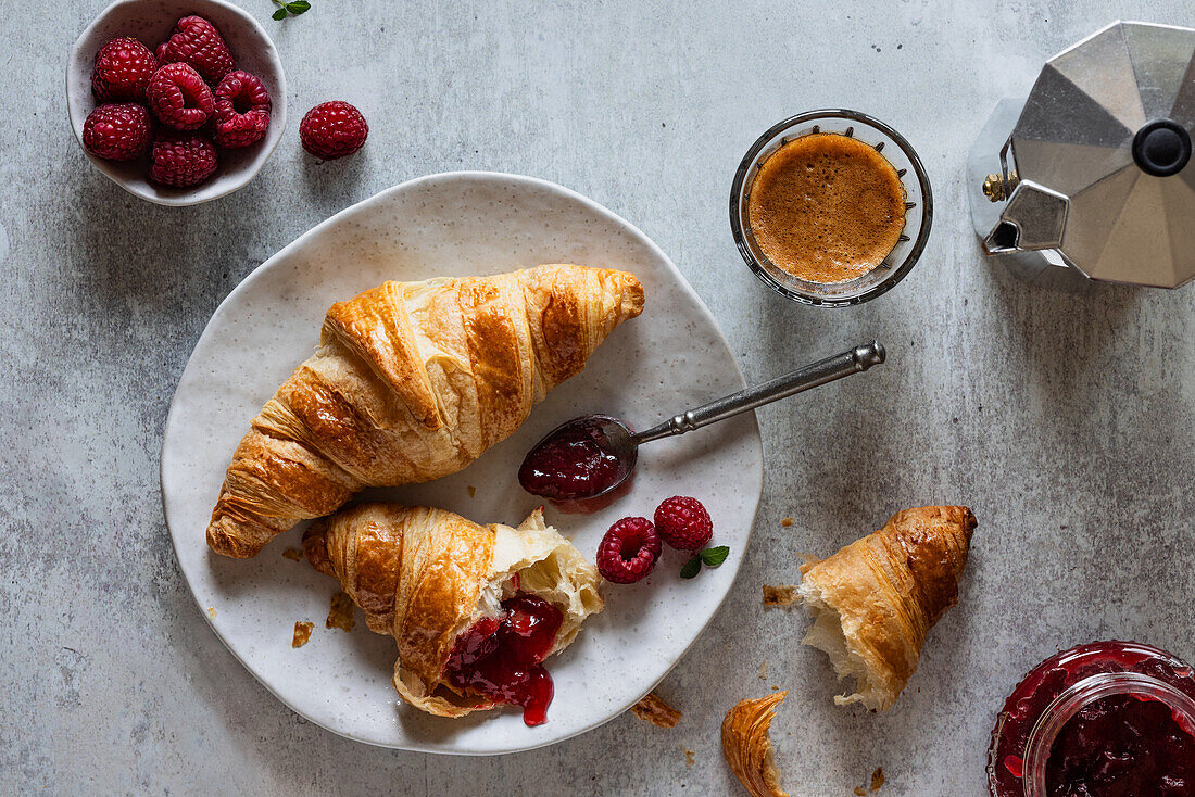 Frühstück mit Croissants, Konfitüre, Himbeeren und Espresso