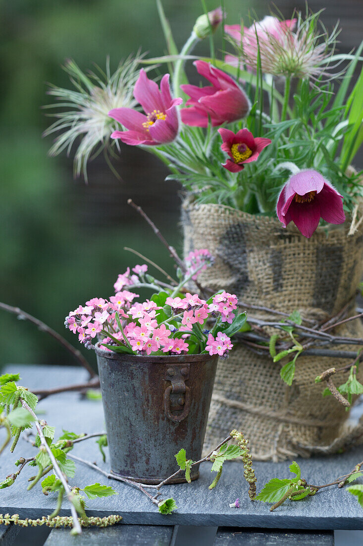 DIY-Vase aus Weckglas und Sackstoff mit Küchenschelle, rosafarbenes Vergissmeinnicht im Vintage Eimerchen