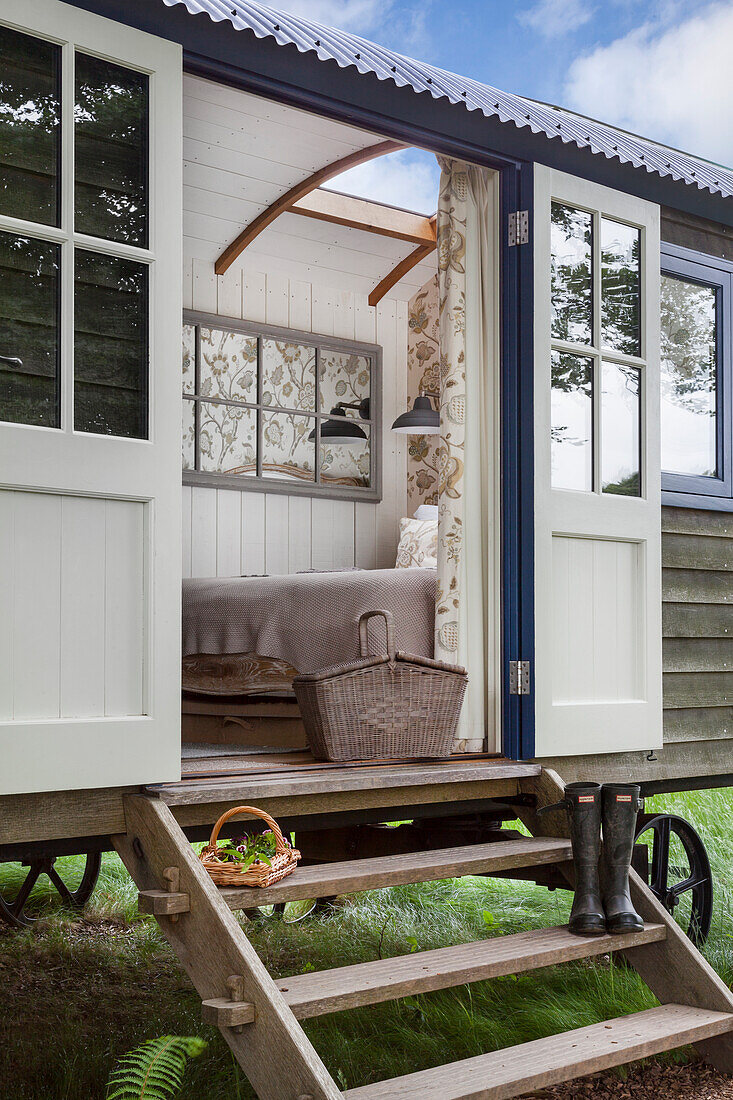 Wooden wagon tiny house with stairs, open entrance, cozy bed