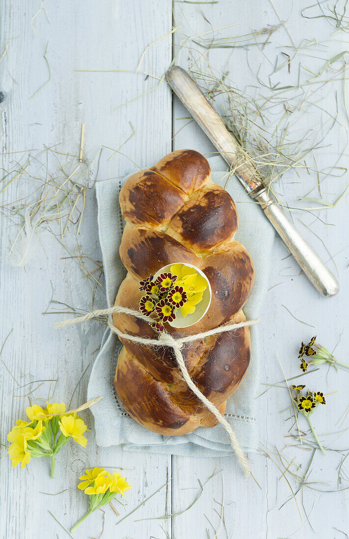 Easter plait with eggshell filled with primrose and cowslip, tied with string on linen cloth, flower decoration