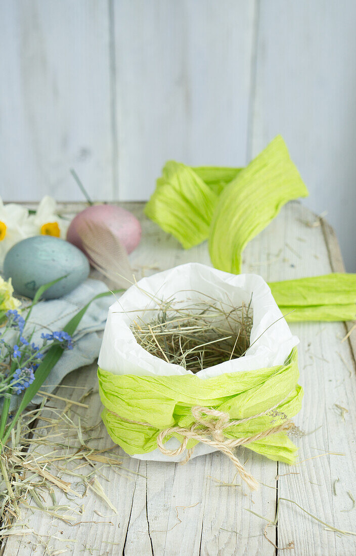 Osternest in Papiertüte mit Heu neben Ostereiern