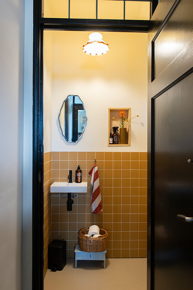 Small guest bath with orange-brown tiles and wall mirror