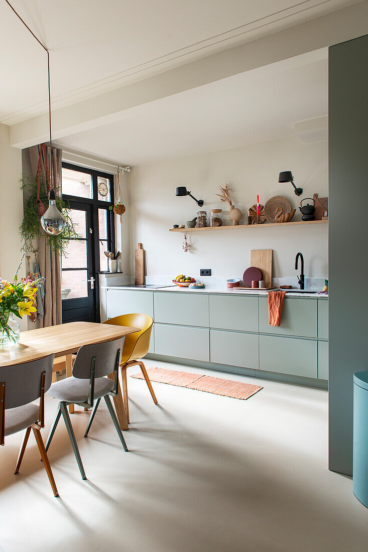 Modern kitchen with green base cabinets and dining area with different chairs