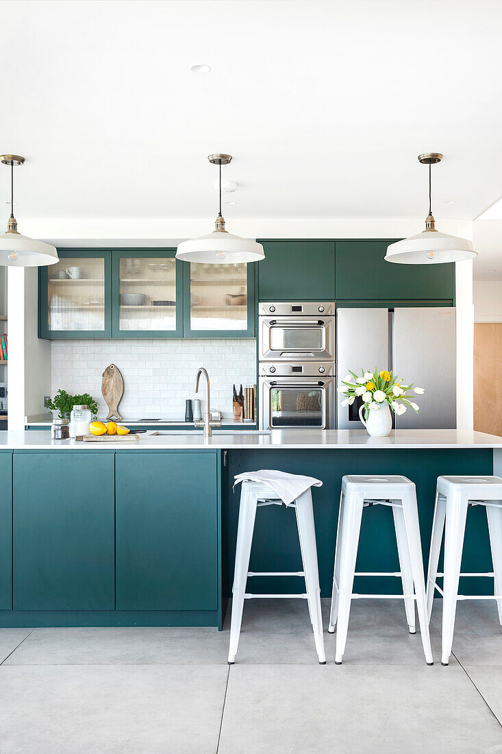 Kitchen with green-blue cabinets, kitchen island and metal bar stools