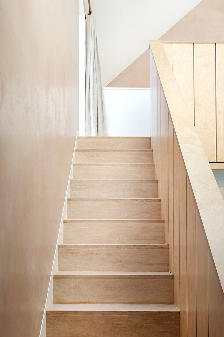 Staircase in light-colored wood with a minimalist design and light-colored walls