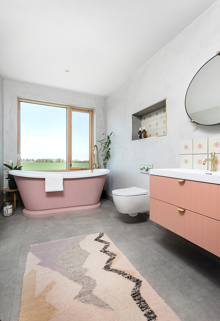 Modernes Badezimmer mit freistehender rosa Badewanne und gemustertem Teppich