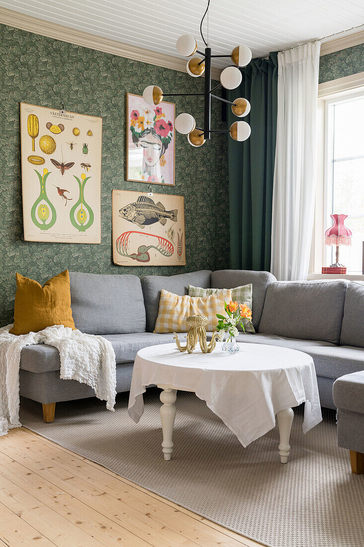 Grey corner sofa with round coffee table and retro wall pictures