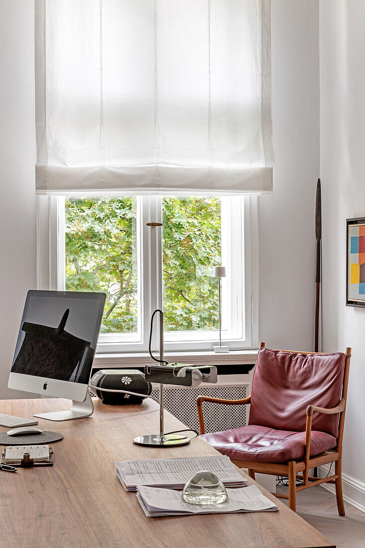 Heimisches Büro mit modernem Schreibtisch und Ledersessel