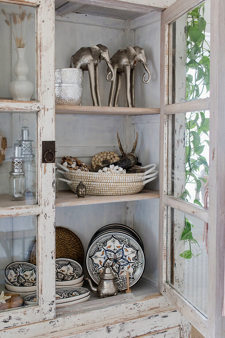 Display cabinet with crockery and decorative objects in ethnic style