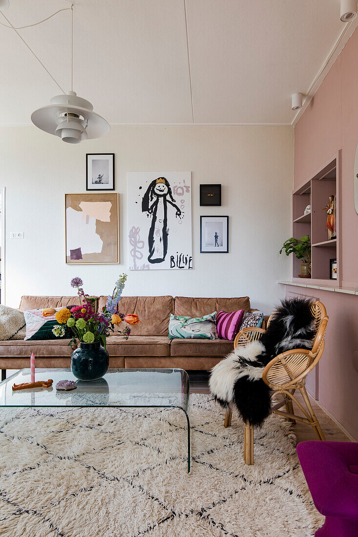 Living room with brown leather sofa, glass coffee table and murals