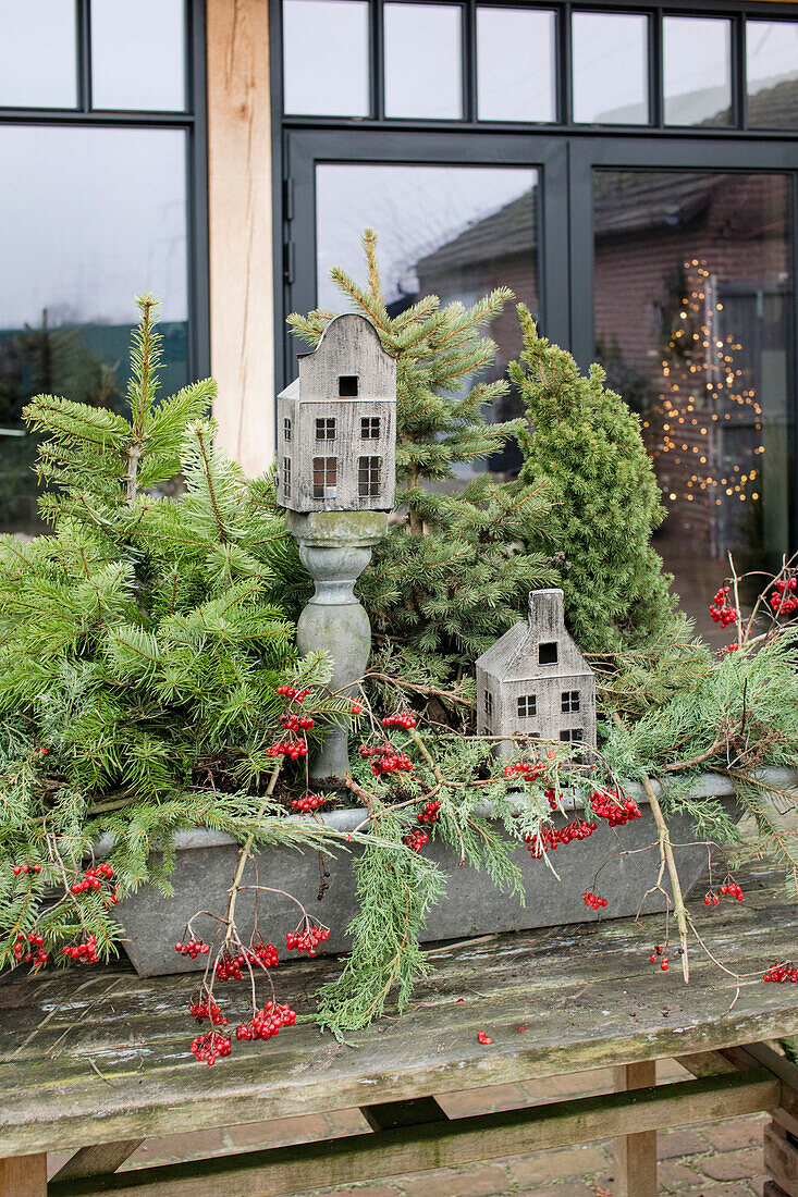 Winter decoration with coniferous branches, berries and wooden model houses