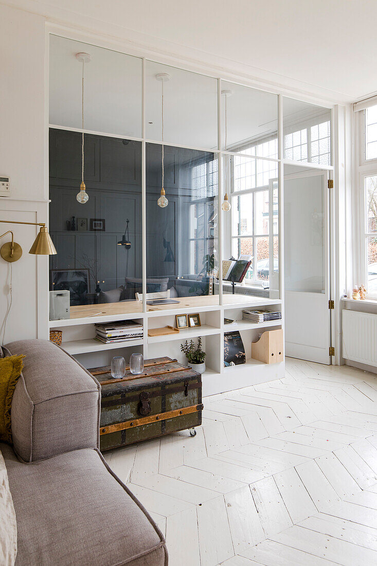 Bright study with glass partition wall and vintage chest as a coffee table