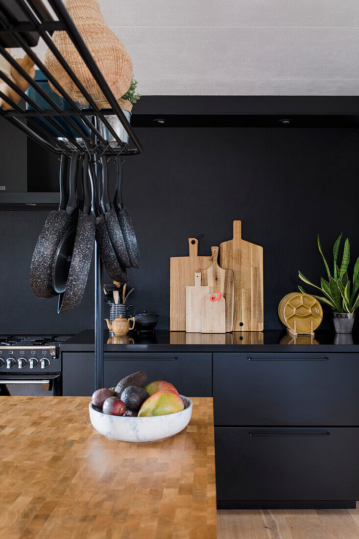 Moderne Küche mit schwarzen Fronten und Kücheninsel mit Holzarbeitsplatte