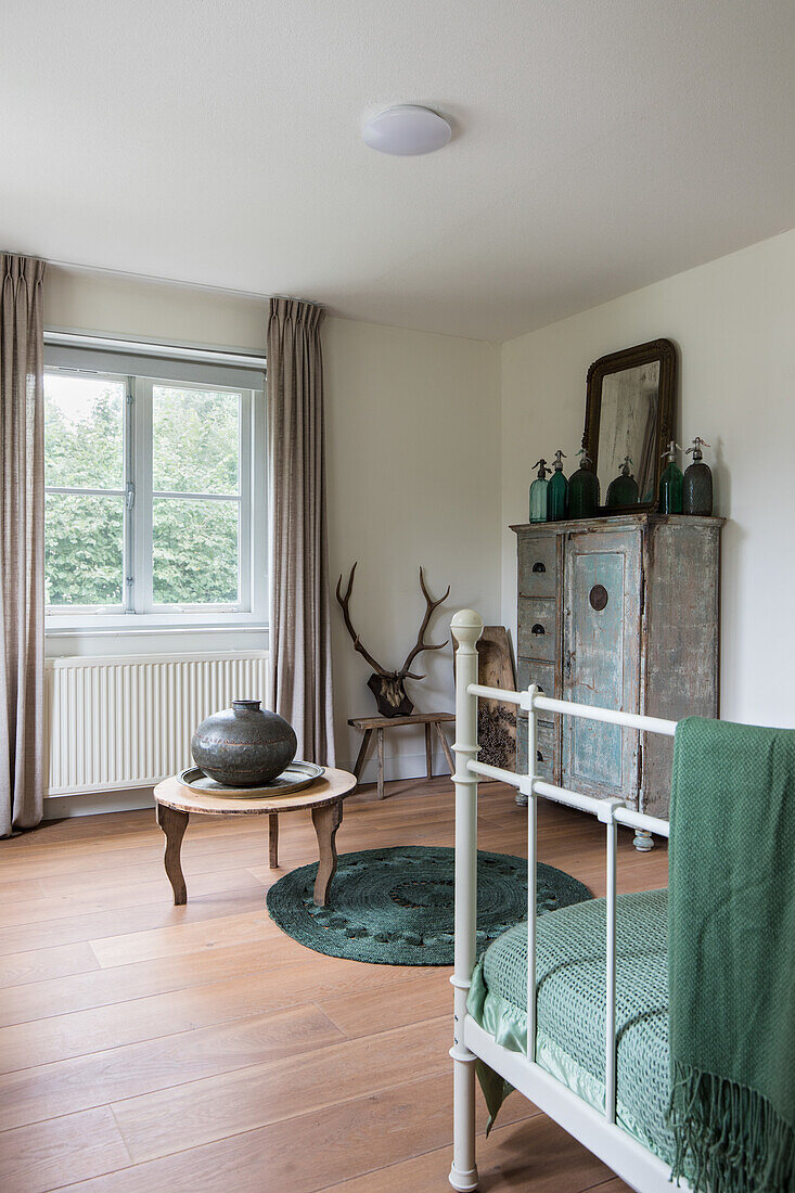 Metal bed with green bedspread in a rustic bedroom