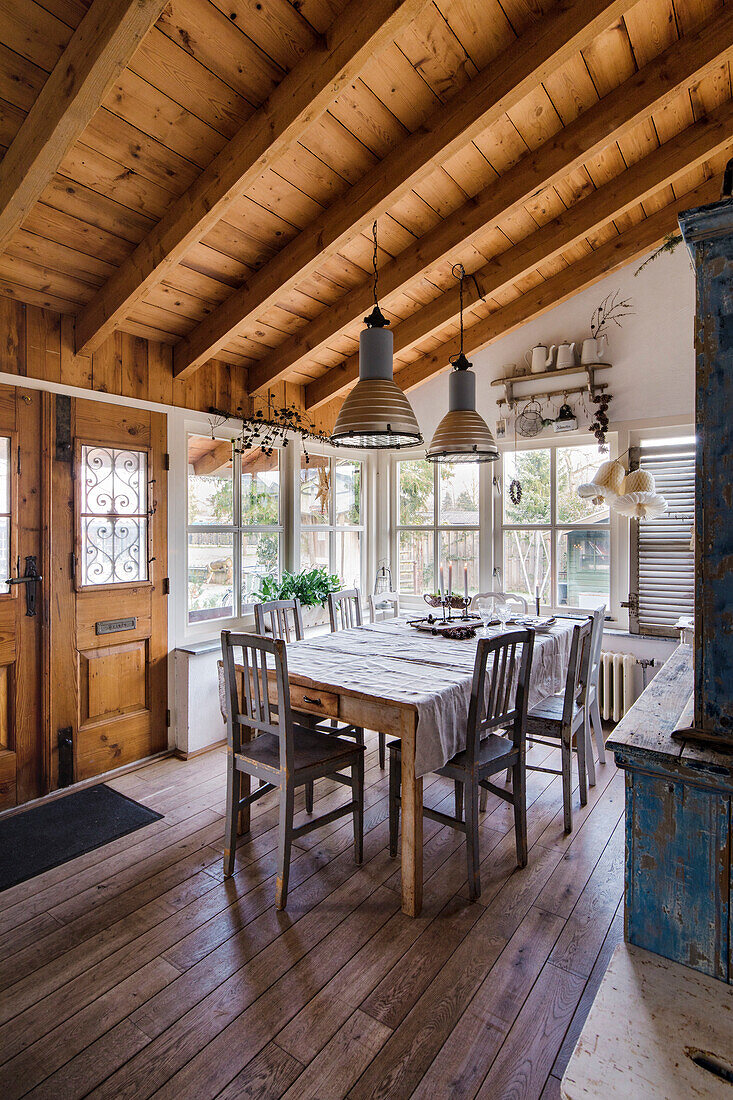 Rustikaler Essbereich mit Holztisch, Metallpendelleuchten und Sichtbalken