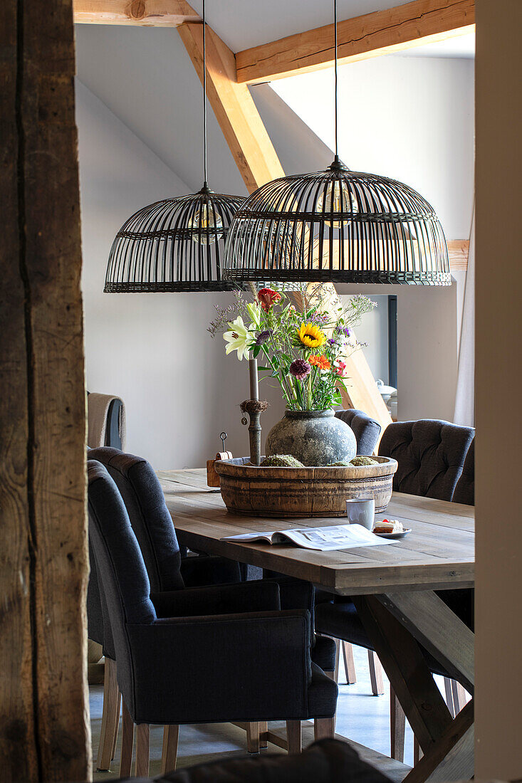 Rustic dining table with cage pendant lights and floral arrangement