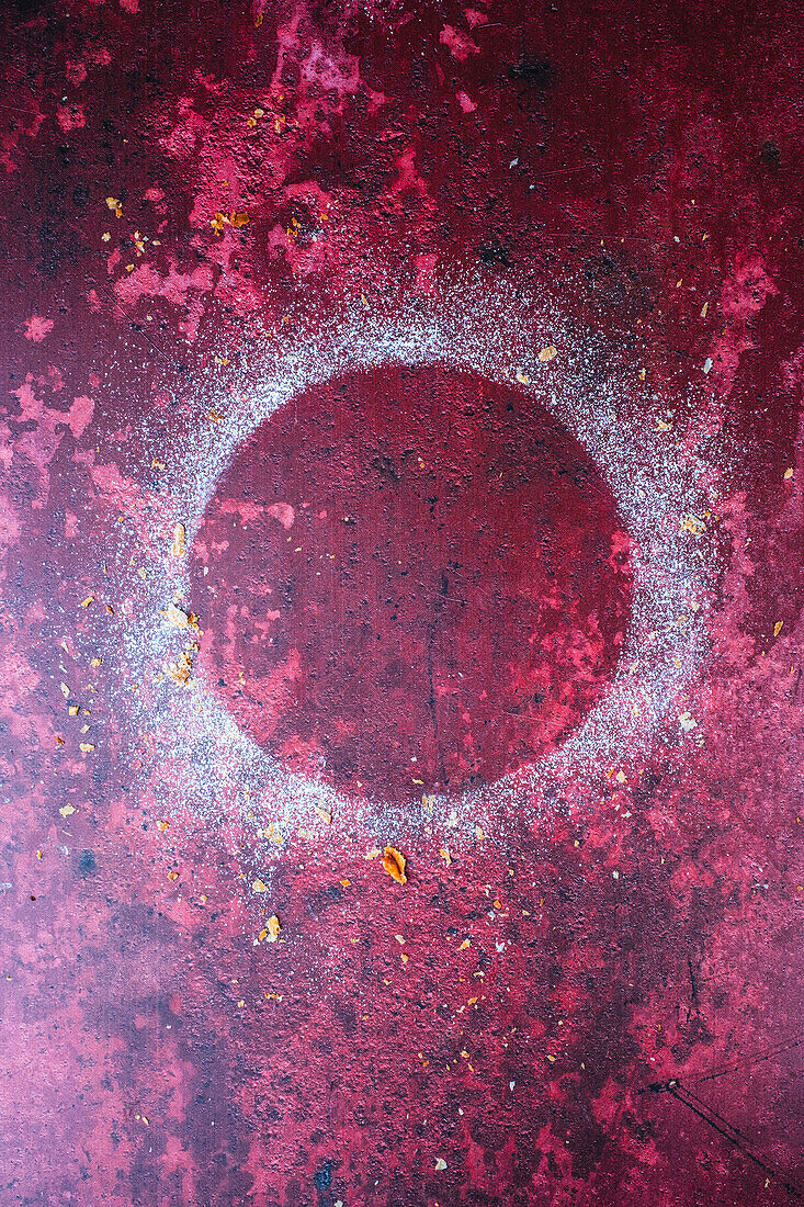 Kreisförmiger Puderzuckerabdruck auf rotem Untergrund