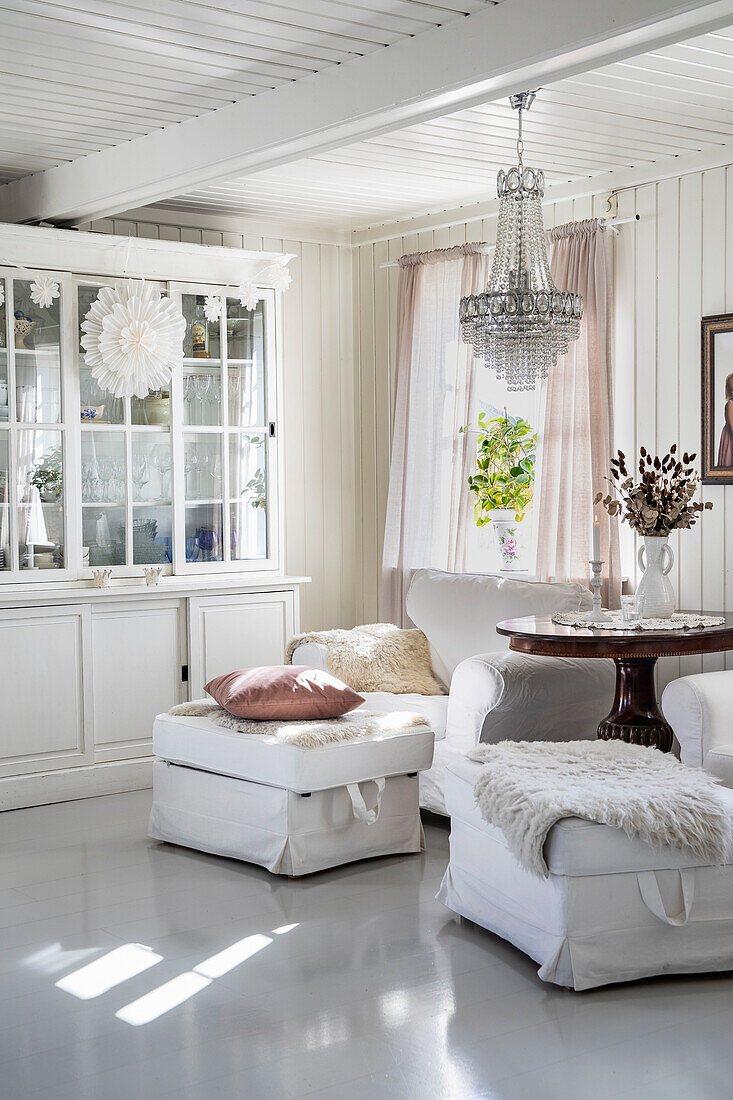 Bright living room with crystal chandelier and white furniture