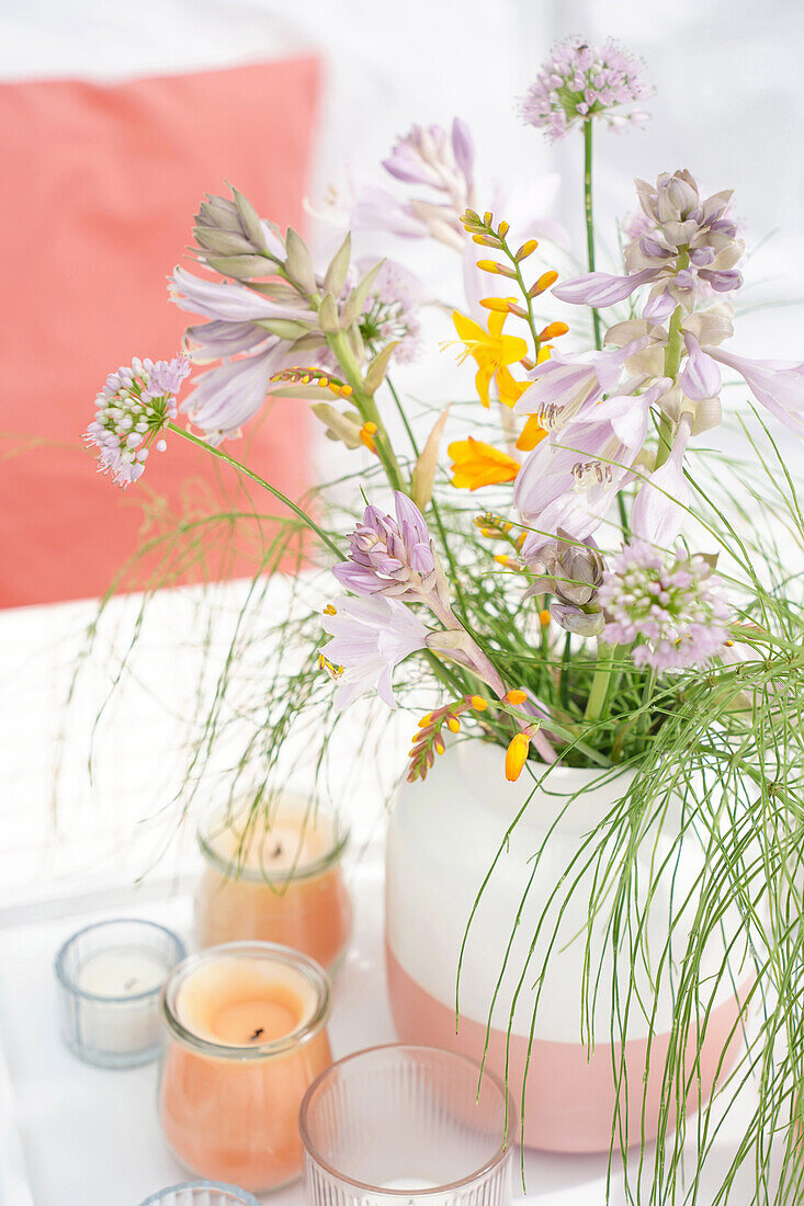 Vase with summer flowers and candles on table