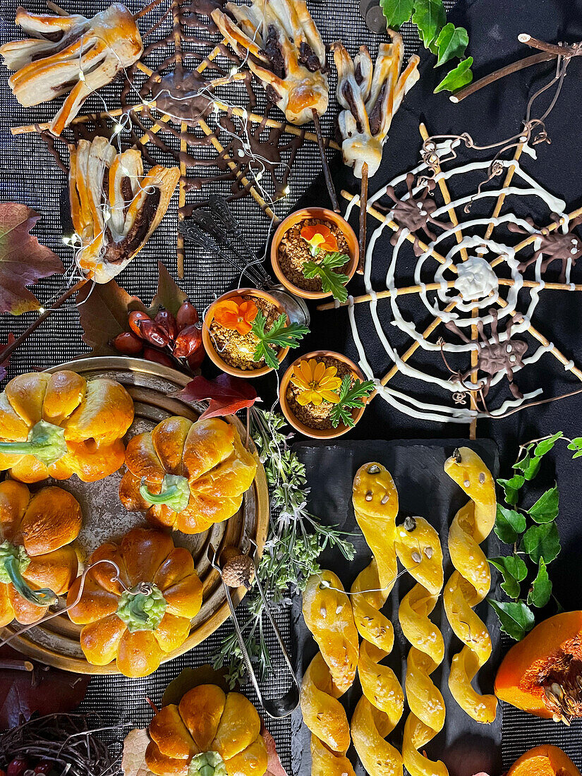 Gefüllte Mini-Kürbiskuchen, Salzstangen in Schlangenform und Schoko-Besen und Spinnennetz zu Halloween