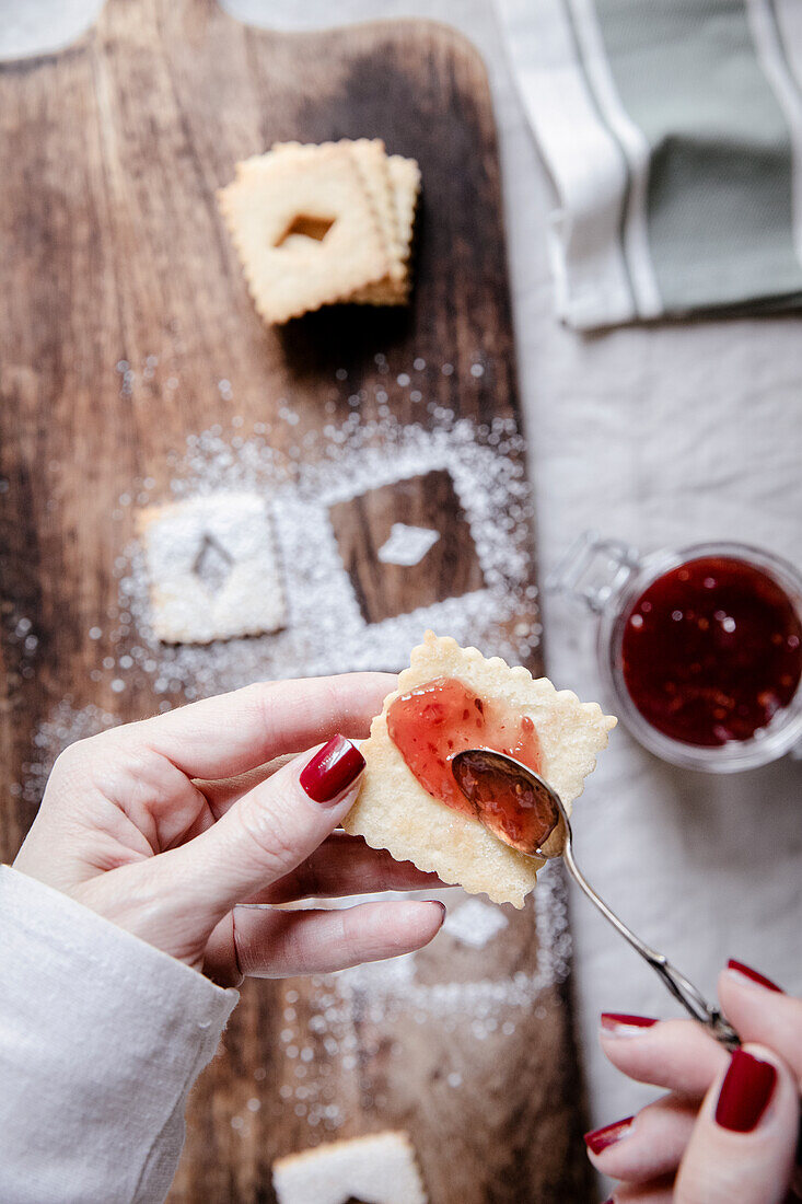 Linzer Plätzchen mit roter Beerenmarmelade bestreichen