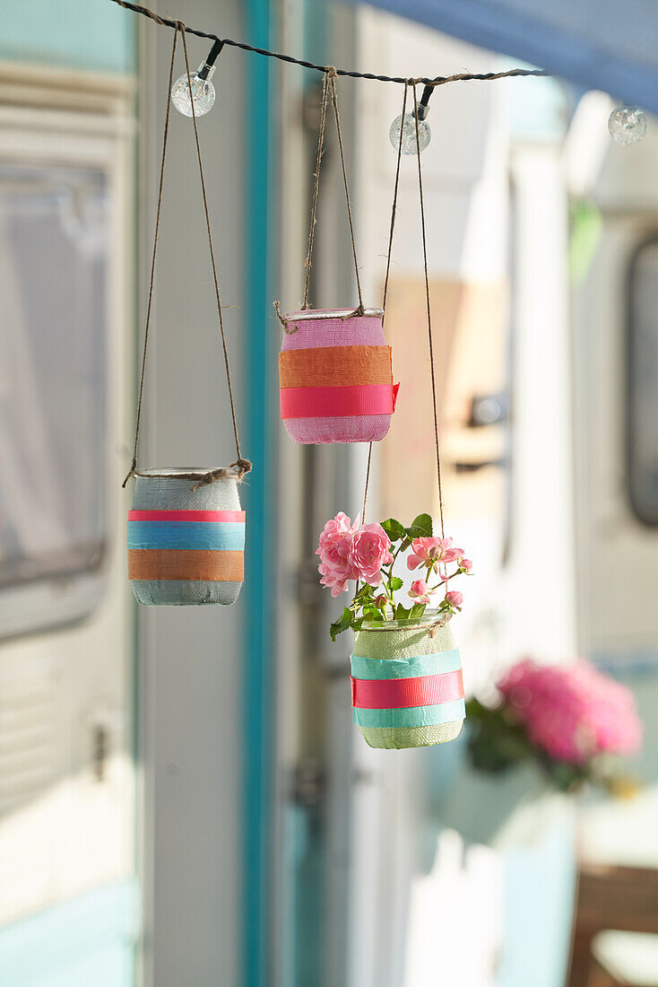 Hanging glass flower pots decorated with tape and pink flowers