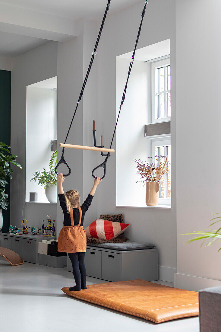 Child playing with gymnastic rings on the ceiling in the living room