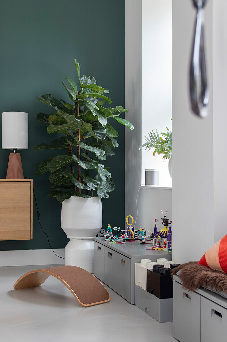 Children's play area with Lego bricks, fig tree (Ficus lyrata) and wooden wobble board