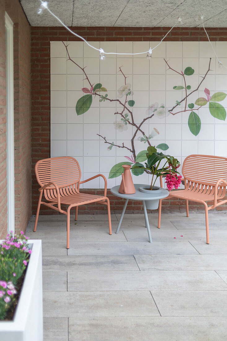 Moderne Terrasse mit Wandbild und rosa Metallstühlen