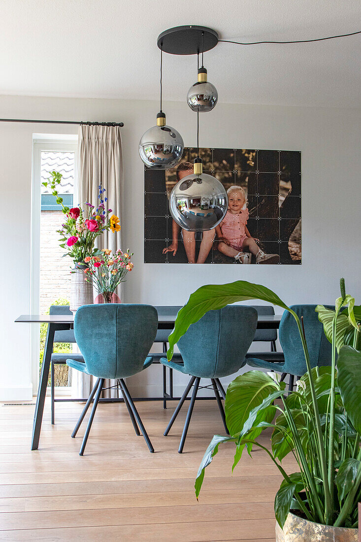 Dining room with blue chairs, round pendant lights and flower arrangement on table