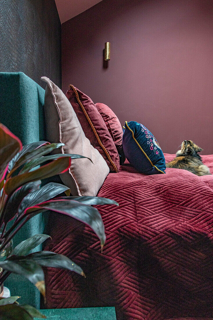 Bedroom with burgundy textiles and green headboard