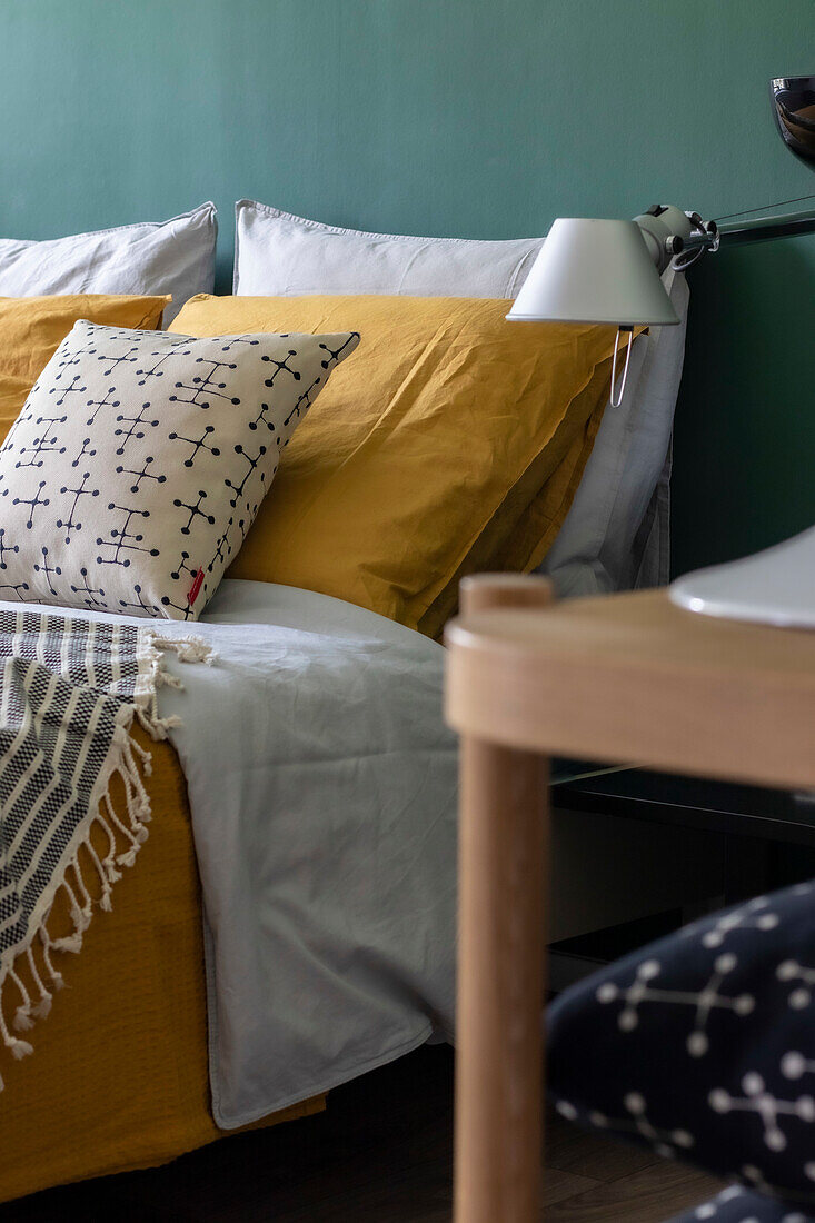 Bed with mustard yellow bed linen and graphic patterned pillow