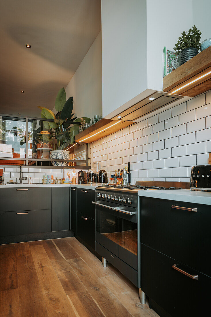 Kitchen with black cupboards, white metro tiles and wooden floor